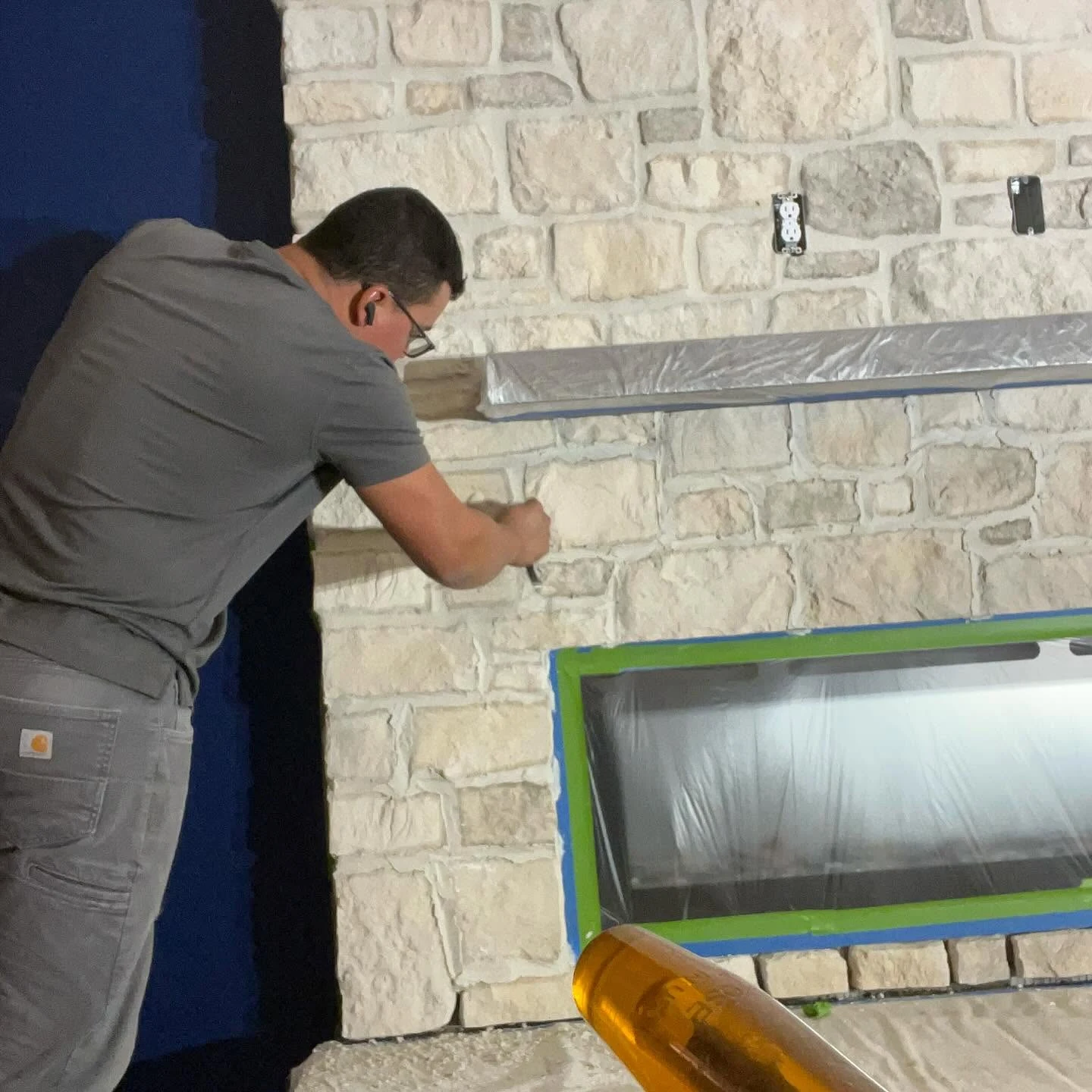 A mason carefully finishing the joints of a stone fireplace